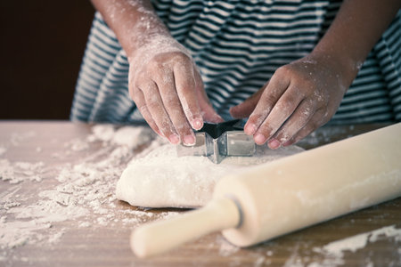 Little child girl hands kneading dough prepare for baking cookies in vintage color tone