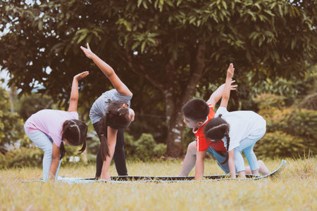 Happy children doing exercise together in the park in summer timeの写真素材