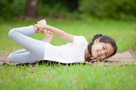 Cute asian little child girl doing exercise in the summer parkの写真素材