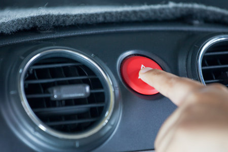 Woman finger pressing emergency button on car dashboard in vintage color tone