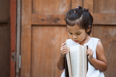 Cute asian child girl  opening a book she love to read a bookの写真素材