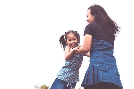 Happy mother holding her kid and spinning around with fun in the park in vintage color toneの写真素材