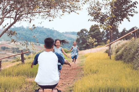 Two asian little child girls running to their father to give a hug with love in the park in vintage color toneの写真素材
