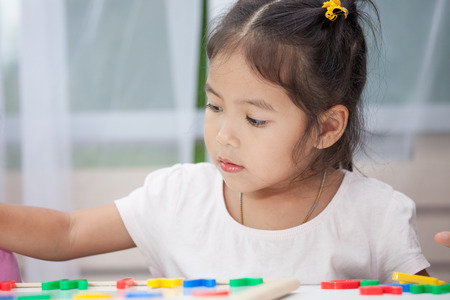 Cute little child girl having fun to play and learn magnetic alphabets on board in the roomの写真素材