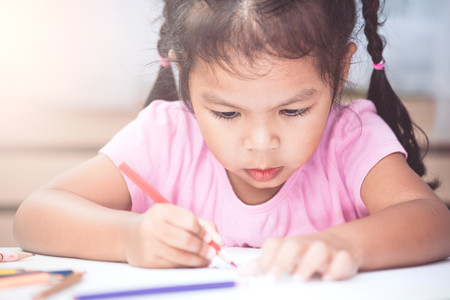 Cute asian child girl having fun to draw and paint with crayon in vintage color toneの写真素材