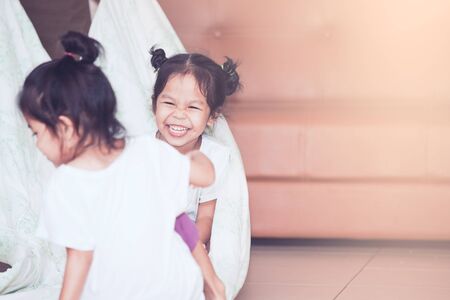 Happy asian child girl laughing and having fun to play with blanket and sister in the house in vintage color toneの写真素材
