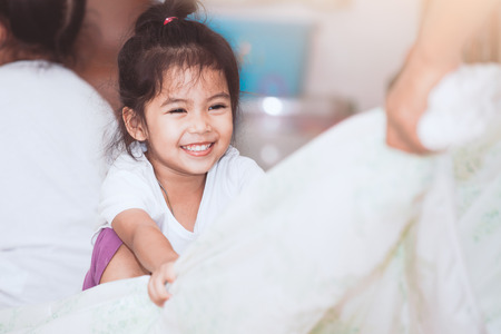 Happy asian child girl smiling and having fun to play with blanket in the house in vintage color toneの写真素材