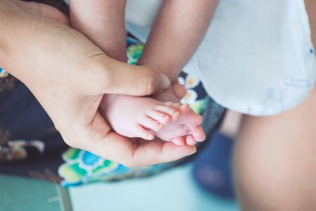 Newborn baby feet on mother hand with tendernessの写真素材