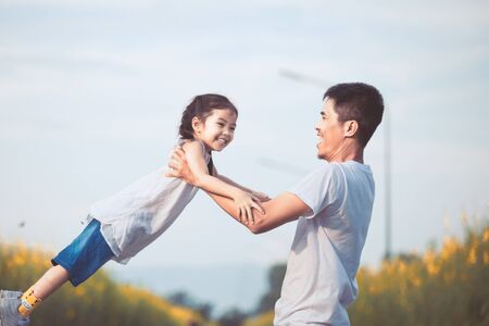 Happy asian father holding his kid spinning around with fun in the park in vintage color toneの写真素材