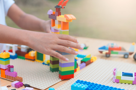 Asian little child girl hand playing with colorful blocks. She is creating and building her toy with fun in good weather outside.の写真素材