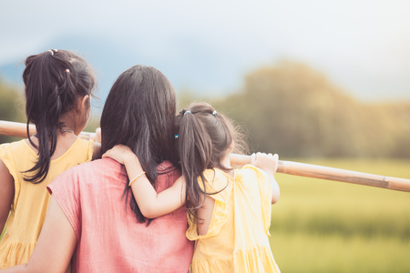 Mother and two asian little child girls looking at beautiful nature in the cornfield together in vintage color toneの写真素材