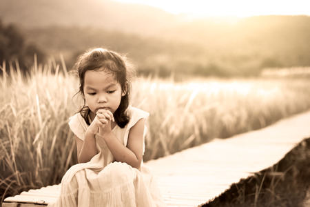Lonely and sad little girl sitting on bamboo walkway in the paddy field in vintage color toneの写真素材