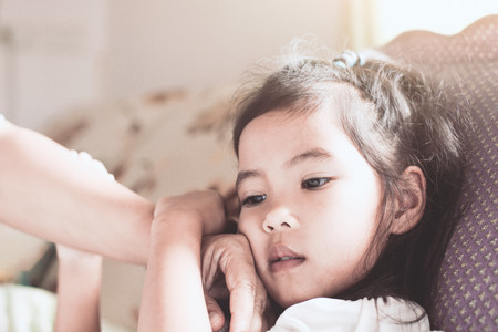 Cute asian child girl sickness and mother hand touch her face to check temperature with love and careの写真素材
