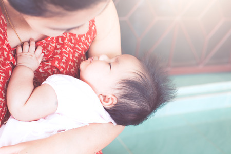 Cute asian newborn baby girl sleeping on mother's shoulder.Mom cuddling baby with tenderness.の写真素材