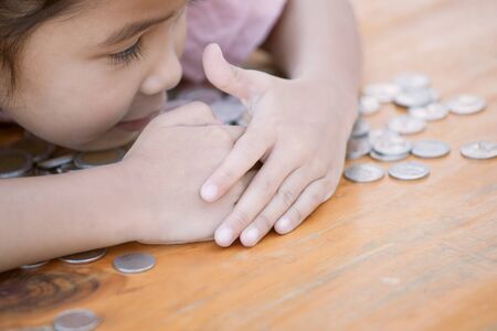Cute asian little child girl hugging and stingy her money. Kid saving money for the future conceptの写真素材