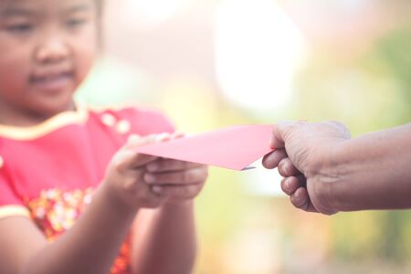 Parent give money in  red envelope to little child girl for celebrate in Chinese New Yearの写真素材