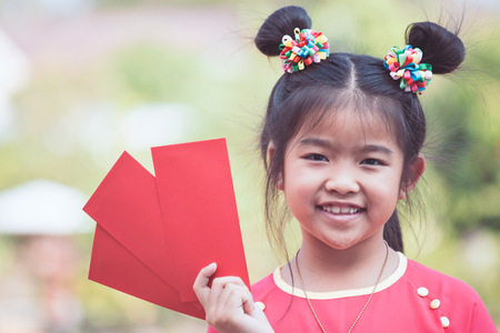 Cute asian child girl holding red envelope and wishing you a happy in Chinese New Yearの写真素材
