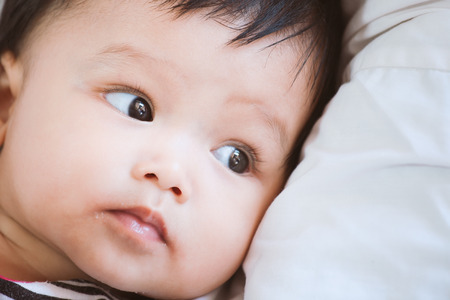 Portrait of cute asian baby girl lying down on her bedの写真素材
