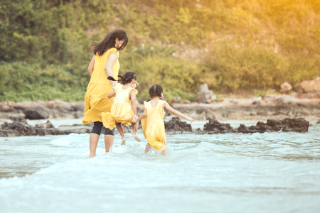 Young asian mother and cute little daughter walking and playing together on beach in summer vacationの写真素材