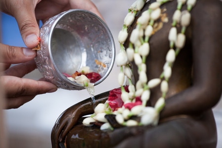Woman hand hold little bowl to bath Buddha statue for blessing ceremony celebrate Songkran in new year water festival, Thai culture concept.の写真素材