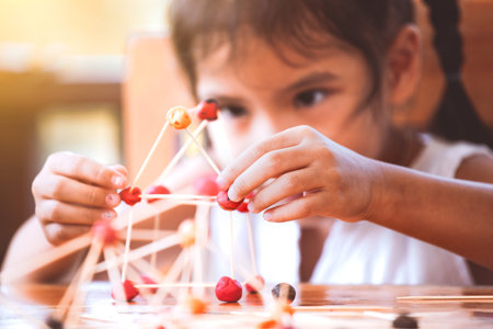 Cute asian child girl playing and creating with play dough and toothpick. Child concentrated with...
