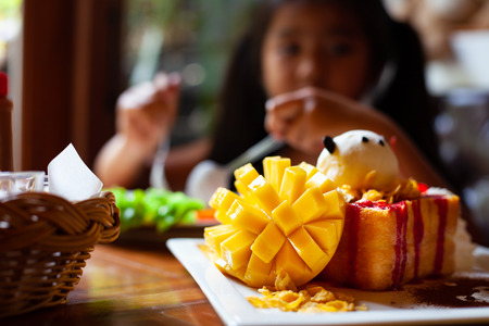 Delicious honey toast with slice mango and ice cream dessert for kid after mealの写真素材