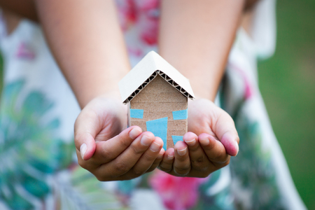 Child holding paper house in hands as real estate and family home conceptの写真素材