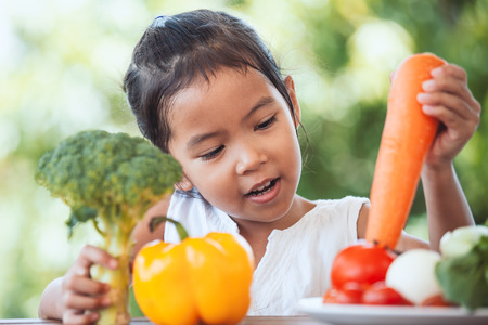 Cute asian child girl learning about vegetables with happinessの写真素材
