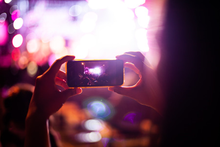 People taking photographs with smart phone during Live music concert and crowd in backgroundの写真素材