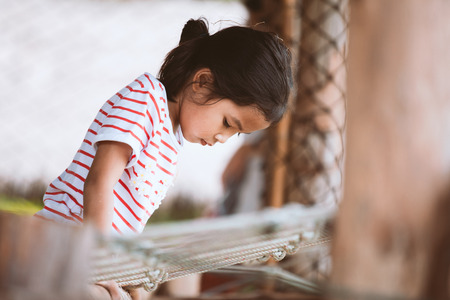 Cute asian child girl having fun to climb and play in the playground with happinessの写真素材
