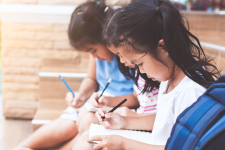 Back to school. Group of asian children reading a book and writing a notebook together with fun and happinessの写真素材