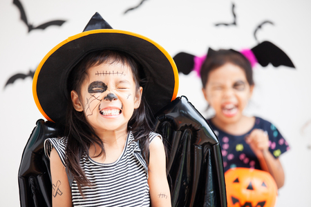 Happy asian little child girl in costumes and makeup having fun on Halloween celebrationの写真素材