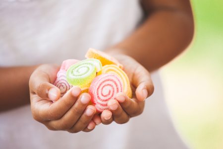 Cute asian child girl holding jelly candies in hand and sharing to otherの写真素材