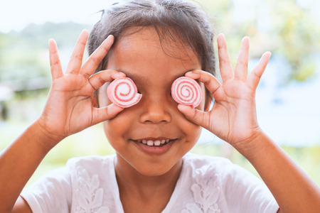 Cute asian child girl with jelly candies smiling and making a funny faceの写真素材