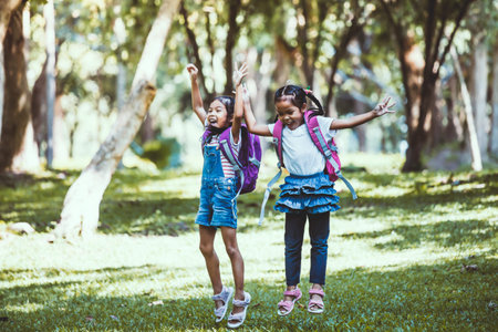 Two cute Asian child girl having fun to play and jump together in the park in vintage color tone