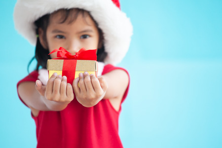 Cute asian child girl wearing santa hat and holding beautiful gift in hand on Christmas celebrationの写真素材