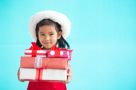 Cute asian child girl wearing santa hat and holding beautiful gift in hand on Christmas celebrationの写真素材