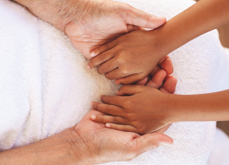 Hands of asian child girl holding elderly grandparent hands wrinkled skin with feeling care and love