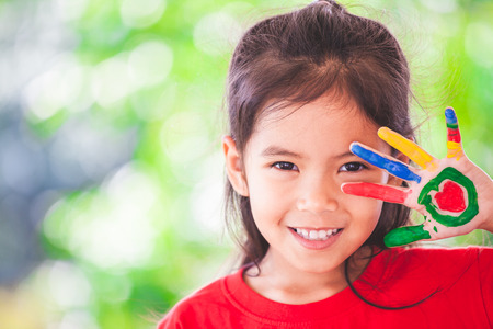 Cute asian little child girl with painted hands smiling with fun and happinessの写真素材