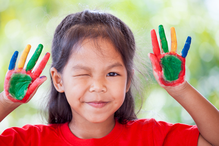 Cute asian little child girl with painted hands smiling with fun and happinessの写真素材