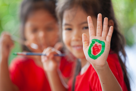 Child drawing and painting a heart on her hand with funの写真素材