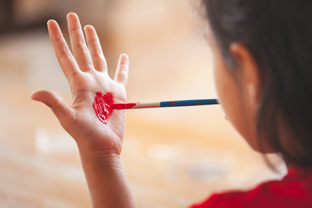 Child drawing and painting a heart on her hand with funの写真素材