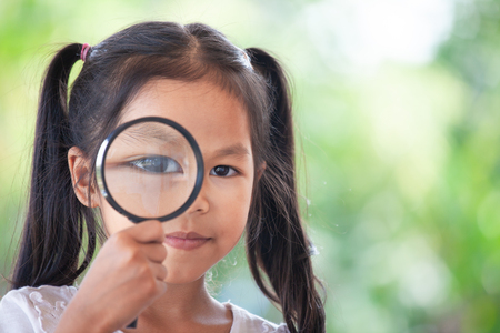 Closeup of asian child girl looking through a magnifying glassの写真素材