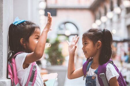 Back to school. Two cute asian child girls with school bag playing together after school in the schoolの写真素材