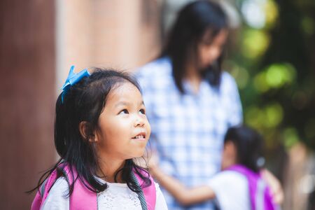 Back to school concept. Cute asian child girl waiting her sister go to school together after hug their motherの写真素材