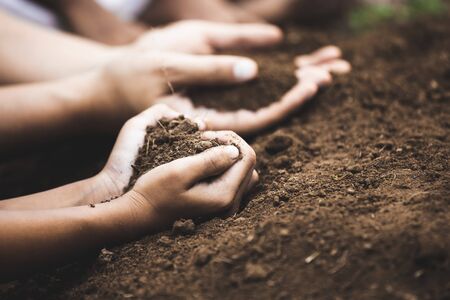 Child and parent holding soil in heart shape prepare for plantingの写真素材