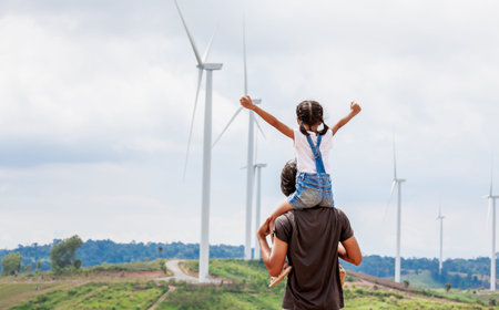 Father and daughter having fun to play together. Asian child girl riding on father's shoulders in the wind turbine fieldの写真素材