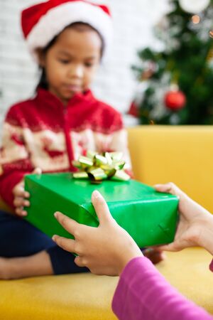 Parent giving Christmas gift box to cute asian child girl on Christmas celebrationの写真素材