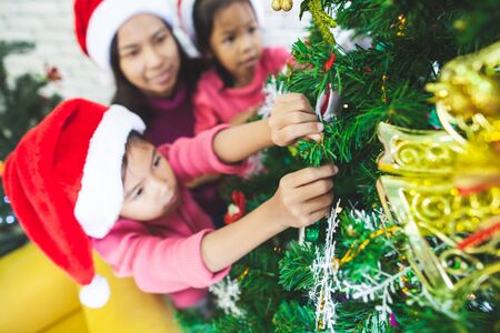 Cute asian child girls and their mother are decorating christmas tree for celebrate on Christmas festival together with funの写真素材