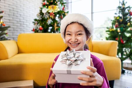 Cute asian child girl surprise with gift and holding beautiful gift in hand on Christmas celebrationの写真素材